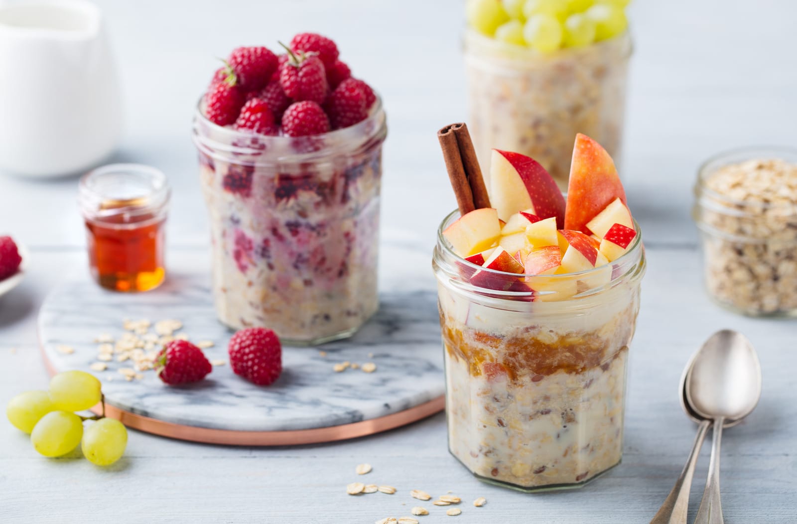 A bowl of creamy overnight oats topped with fresh berries, served with a spoon and garnished with mint leaves.