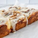 A close-up view of freshly baked cinnamon rolls topped with creamy icing, perfect for a delicious breakfast or brunch treat.