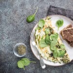 Delicious spinach and feta omelet served on a plate with fresh spinach leaves and slices of whole grain bread.